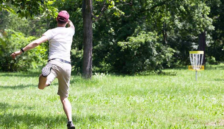 Disc golfer throwing an approach shot towards the goal