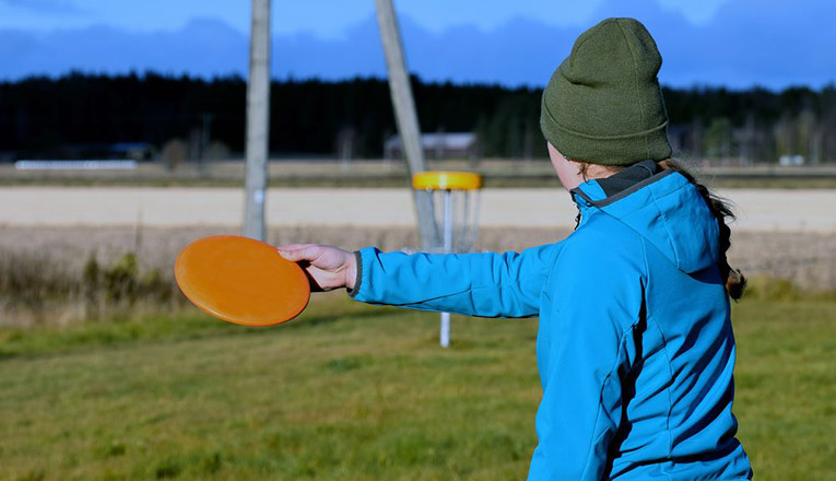 young woman aiming disc to target